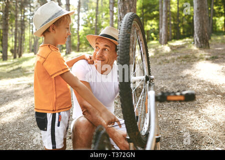 Padre e figlio riparare una bicicletta nel parco. Foto Stock