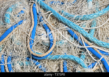 Close up sullo sfondo di un mucchio di bobine di pesca in mare net con colorate galleggianti vivaci e corde di cavo a porto Foto Stock