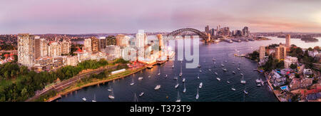 Ampia panoramica paesaggio urbano della città di Sydney CBD pietre miliari sul lungomare del porto di Sydney su Lavender Bay da North Shore al tramonto. Foto Stock
