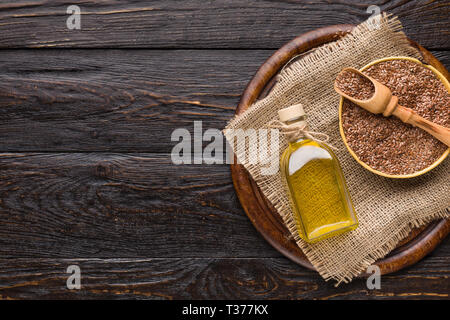 Olio di semi di lino e bottiglia di i semi di lino su sfondo di legno. Foto Stock