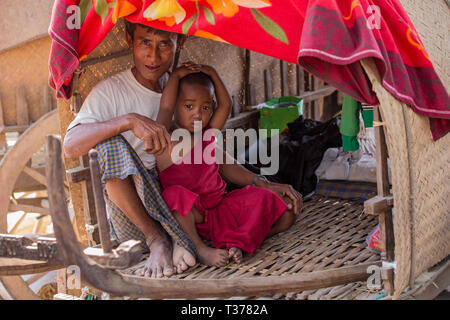 Padre e il debuttante monaco buddista in oxcart al Vesak luna piena festival per festeggiare il compleanno di Buddha a Shwe Yin Pagoda Maw, Thazi, Myanmar Foto Stock