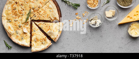 Cheesy pizza e vari tipi di formaggi sulla tabella grigia, vista dall'alto Foto Stock