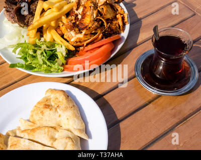 Döner Kebab sul piatto con patatine fritte, pomodori e cipolla e insalata. Pollo alla griglia e carne di agnello con verdura e pane pita. Foto Stock