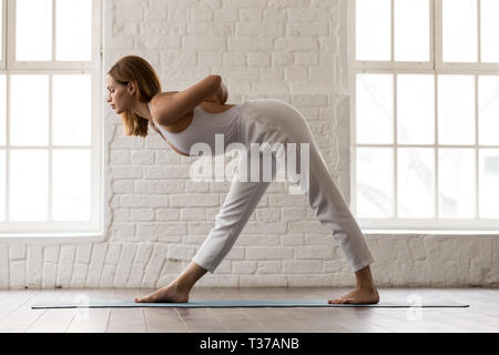 Donna in piedi in posa Parsvottanasana, una facciata di piegatura esercizio di yoga Foto Stock
