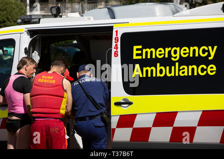 Surf volontario di soccorso e personale paramedico partecipare ad un vicino annegato uomo a Palm Beach come egli risiede in ambulanza,Sydney , Australia Foto Stock