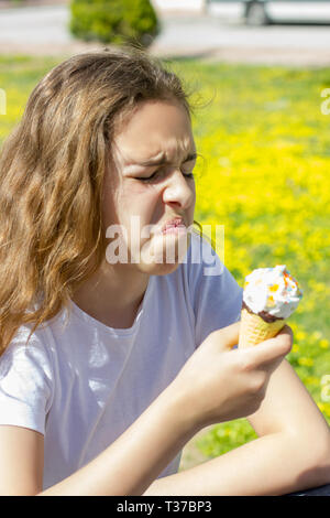 Insoddisfatto infelice ragazza teen mangia insapore gelato in cono di cialda in estate Foto Stock