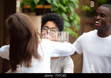 Sorridente americano africano donna abbracciando amico dire ciao a parte Foto Stock