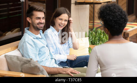 Felice giovane coppia caucasica nozze pianificazione di ascolto di pianificatore africana Foto Stock