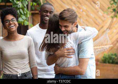 Felice l'uomo e donna saluto abbracciando a multi-etnico Incontro degli amici Foto Stock