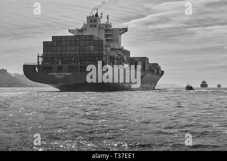 Foto Moody in bianco e nero della nave portacontainer gigante Hyundai Platinum, in corso nel trafficato canale East Lamma, Hong Kong, Cina Foto Stock