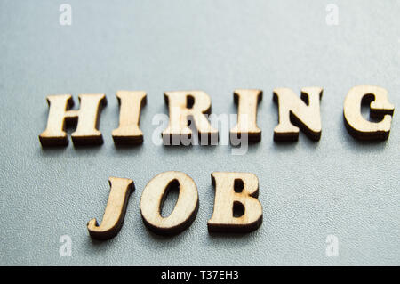 Il concetto di assunzione di lavoratori, scritto da affitto lavoro in lettere di legno su uno sfondo grigio con il fuoco selettivo e lo spazio per il tuo. Foto Stock