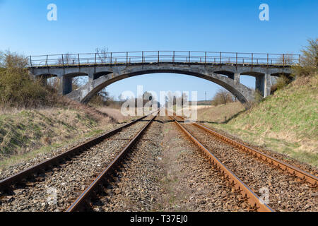 Il vecchio viadotto sopra i binari ferroviari. Ponte di cemento oltre la ferrovia. Stagione della primavera. Foto Stock