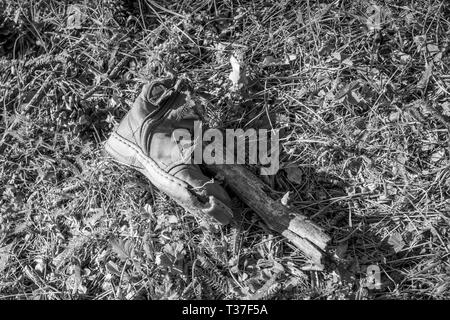 Scartato abbandonato decomponendo il bambino scarpa sulla foresta di erba e elemento di diramazione, immagine in bianco e nero, Pazardzhik regione, Bulgaria meridionale Foto Stock