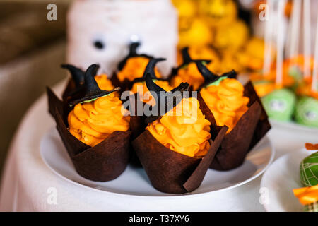 Tortine con crema di colore arancione e nero dolce cappelli sul candy bar per la festa di Halloween. Foto Stock