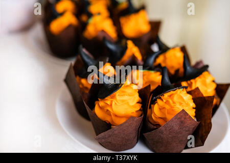 Tortine con crema di colore arancione e nero dolce cappelli sul candy bar per la festa di Halloween. Foto Stock