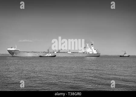Foto in bianco e nero della petroliera grezza (Shuttle Tanker), PETRONORDIC, scortata da 2 rimorchiatori, si avvicina alla raffineria petrolifera di Fawley, Southampton, Regno Unito Foto Stock