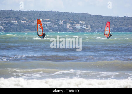 CAN PASTILLA, MALLORCA, Spagna - 6 Aprile 2019: due windsurf con vele rosso in onde verdi su un ventoso e giornata di sole su Aprile 6, 2019 in Can Pastilla Foto Stock