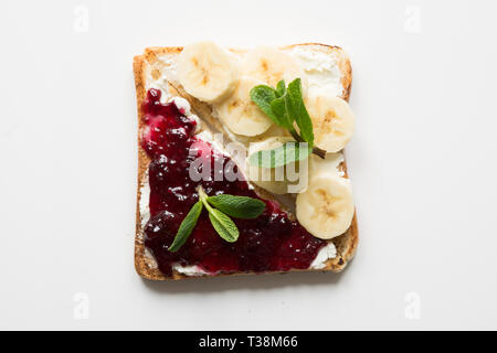 Diversi tipi di panini per una sana colazione per bambini senza zucchero, con marmellata di frutti di bosco, banane. Vista da sopra. Foto Stock