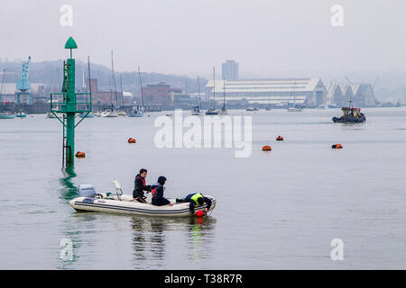 Upnor, Kent, Regno Unito. Tre ragazzi in un dinghy afferrando una stiva di una boa. Foto Stock