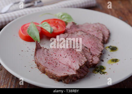 Fette di arrosto di manzo e pomodoro su una piastra Foto Stock