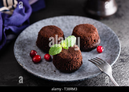 Mini torte al cioccolato decorato con foglia di menta su una piastra Foto Stock