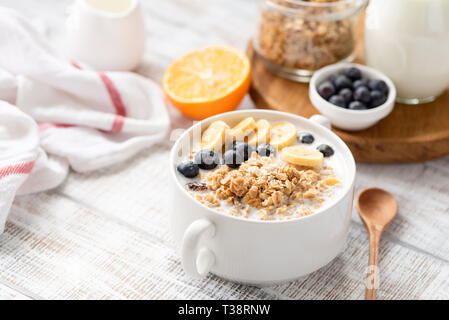 Una sana colazione Granola alimentare con yogurt, frutta in vaso bianco sul tavolo di legno. Messa a fuoco selettiva Foto Stock