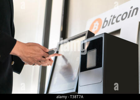 Imprenditore acquisto e trasferimento cryptocurrency per telefono cellulare dal bancomat per le operazioni di acquisto e di vendita cryptocurrency. Foto Stock