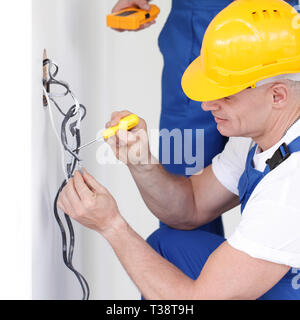 Due costruttori che lavorano con l'elettricità in ambienti chiusi in casa nuova Foto Stock