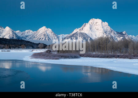 Acque ghiacciate Nella lanca piegare riflettendo la coperta di neve Mount Moran e Teton Mountains in un freddo inverno mattina. Il Parco Nazionale del Grand Teton, Wyoming Foto Stock