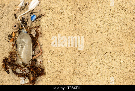 Real la bottiglia di plastica con tappo e paglia di plastica lavati fino sulla spiaggia miscelati con alghe marine e conchiglie di piume. Spazio per il testo Foto Stock