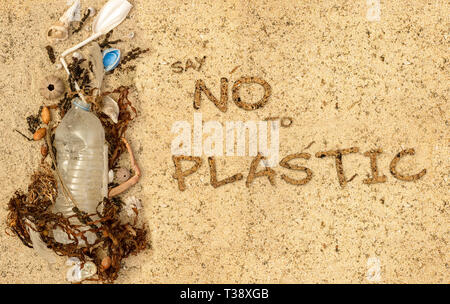 Real la bottiglia di plastica con tappo e paglia di plastica lavati fino sulla spiaggia miscelati con alghe marine e conchiglie di piume. Dire di no al testo in plastica Foto Stock