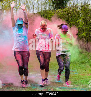 Tre donne guide essendo coperto di vernice sul cancro Macmillan carità 5K colore fun run. Foto Stock