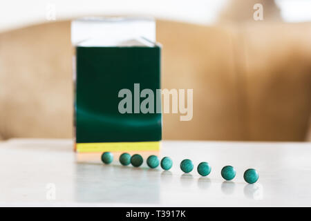 Spirulina pillole in linea su un tavolo accanto a una casella Sfondo. Foto Stock