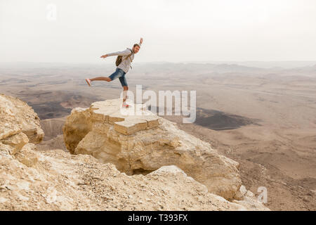 Mitzpe Ramon, Israele - Novembre, 22: Uomo stsnding ona roccia sul bordo del cratere di Ramon scogliera sul deserto del Negev, Israele Foto Stock