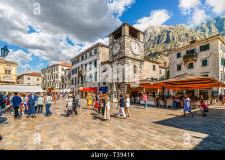 I turisti passeggiata, cenare al caffè e negozi sotto la torre dell orologio nella Piazza delle Armi, nel medievale città murata di Kotor, Montenegro Foto Stock