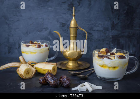 Iftar o snack Suhoor close up di date con yogurt e banane il miele e le date su sfondo nero , concetto del Ramadan Foto Stock