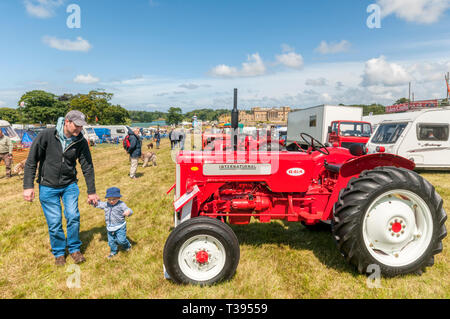 Un padre e figlio guardando i trattori presso la Holkham Country Fair in motivi di Holkham Hall in North Norfolk. Foto Stock