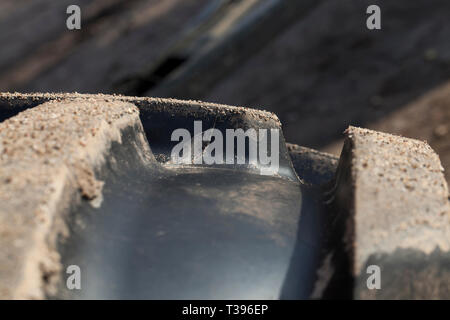 Parte del trattore s grande nero pneumatici in gomma è prevista nel fango e sabbia dopo il dissodamento Foto Stock