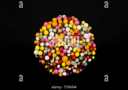 Immagine macro di un 'freckle', cioccolato bud rivestito in spruzzino, isolata su uno sfondo nero Foto Stock