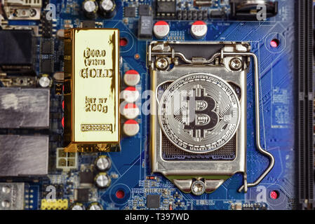 Vista dall'alto del bit d'oro moneta e golden mattone o blocco sul computer scheda madre processore.Bitcoin mining farm, lavorando le attrezzature informatiche concetto. Foto Stock