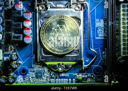 Vista superiore del golden qtum cryptocurrency moneta fisica sul computer scheda madre processore.Bitcoin mining farm, lavorando le attrezzature informatiche concetto. Foto Stock