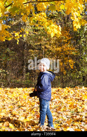 Bambino fotografo in autunno park, cercando e posare la fotocamera A Foto Stock