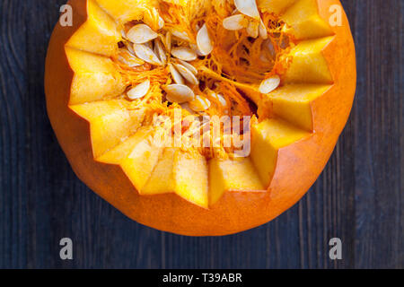 Una zucca piccola tagliata con sharp tacche, vista dall'interno di semi di grandi dimensioni Foto Stock