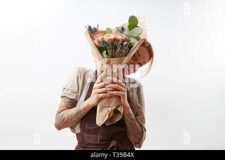 Ragazza sorridente saluto detiene il mazzetto da fragranti fiori bellissimi coralli viventi colorato su sfondo grigio. Copia dello spazio. Concetto Giornata della madre. Foto Stock