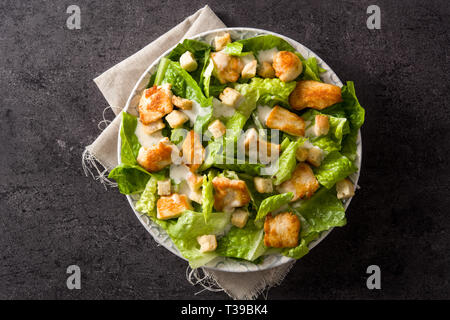 Caesar con insalata di lattuga,pollo e crostini su sfondo nero.vista superiore Foto Stock