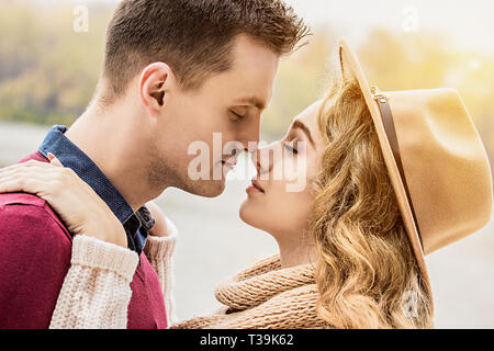 Totalmente nell'amore. Immagine ritagliata della giovane bella giovane mantenendo gli occhi chiusi mentre in piedi vicino faccia a faccia. Coppia giovane in ama camminare all'esterno. Foto Stock