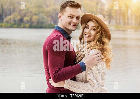 Coppia felice. Ritratto di bella abbracciando giovane cercando di fotocamera e sorridere mentre in piedi all'esterno. Giovane uomo abbracciando la sua bella ragazza Foto Stock