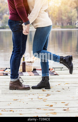 Romantica storia d'amore. Immagine ritagliata della bella giovane tenendo le mani insieme mentre in piedi vicino a ogni altro sul molo in legno. Giovane a piedi Foto Stock