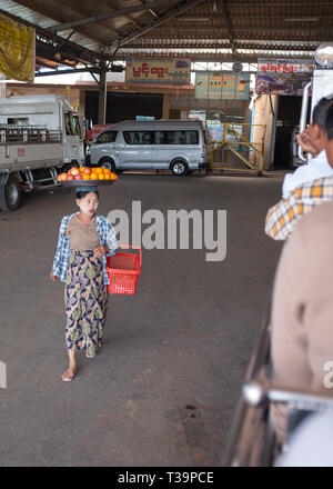 Donna birmano con thanaka face painting che porta una piastra con la frutta in testa alla stazione degli autobus di Kinpun Vlllage,Kyaiktiyo,Myanmar. Foto Stock