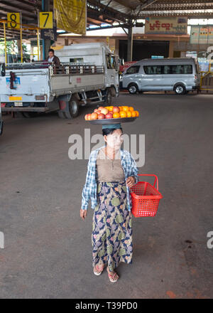 Donna birmano con thanaka face painting che porta una piastra con la frutta in testa alla stazione degli autobus di Kinpun Vlllage,Kyaiktiyo,Myanmar. Foto Stock